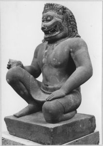 Monstre d'échiffre (corps d'homme et tête de lion), agenouillé, main gauche posée sur la cuisse gauche (vu de 3/4 gauche). EFEO_CAM19566_2